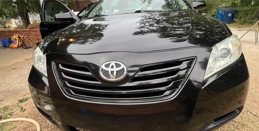 Same black Toyota Camry — paint glossy, headlights clear, ready for the road after Freeman's exterior detail