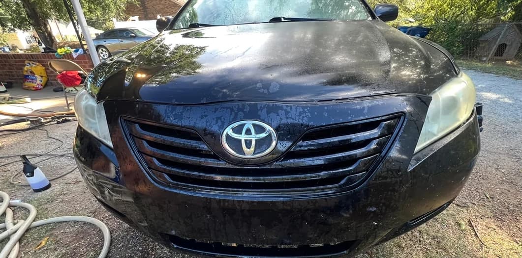 Black Toyota Camry covered in road grime and water spots before exterior detail